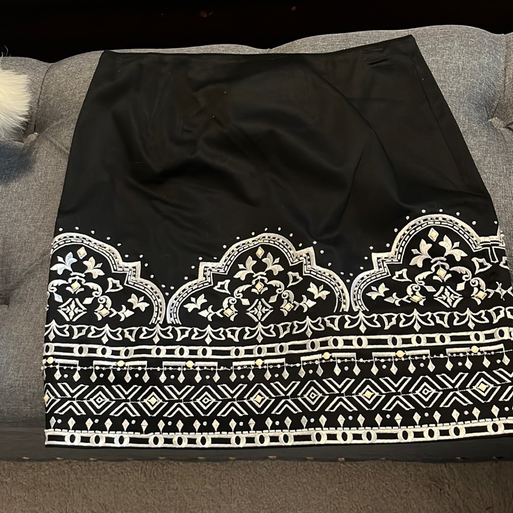 above knee skirt white and silver raised embroidery across bottom.  slim fit.